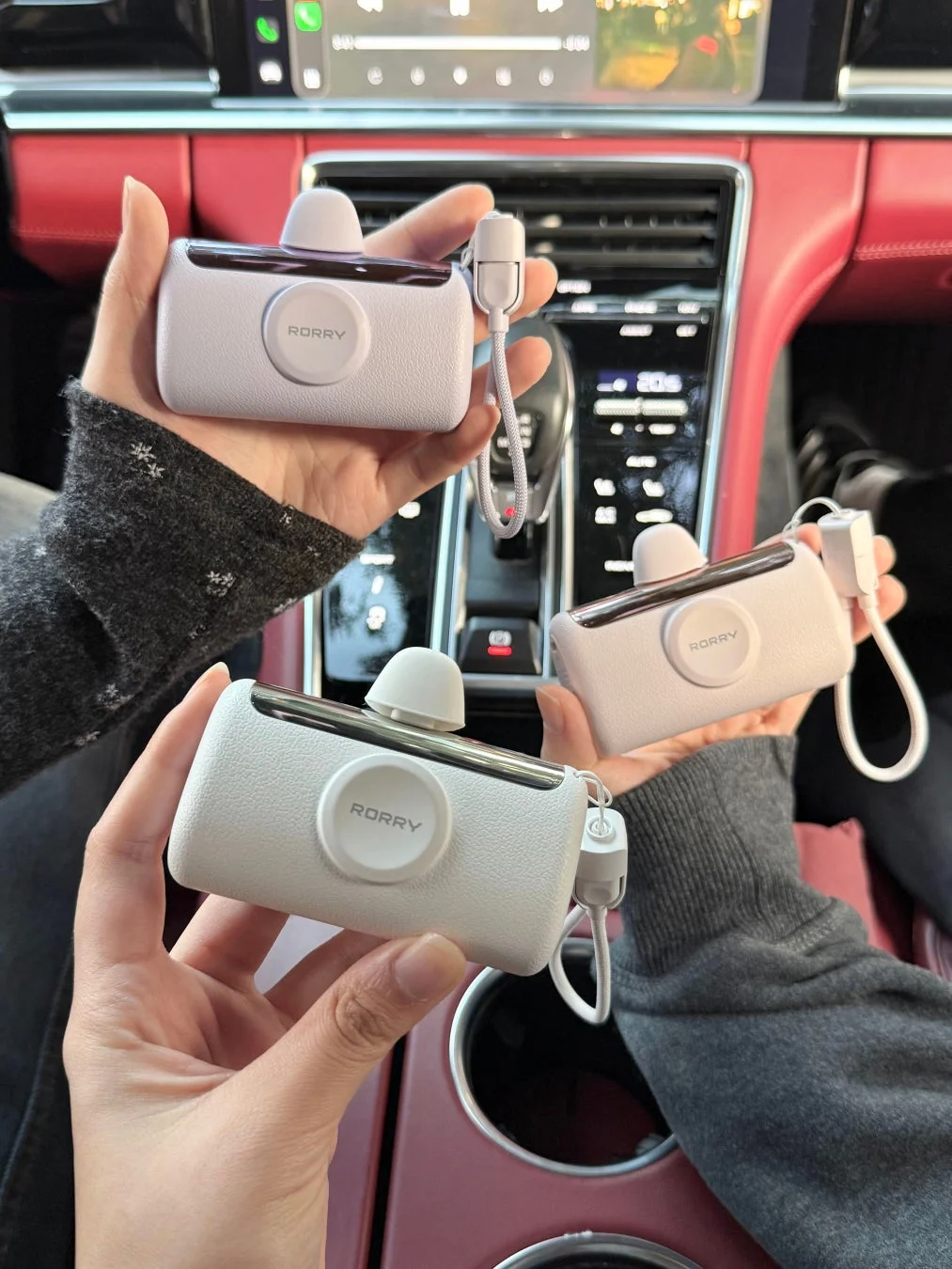 車内で複数の手がモバイルバッテリーを持っている様子