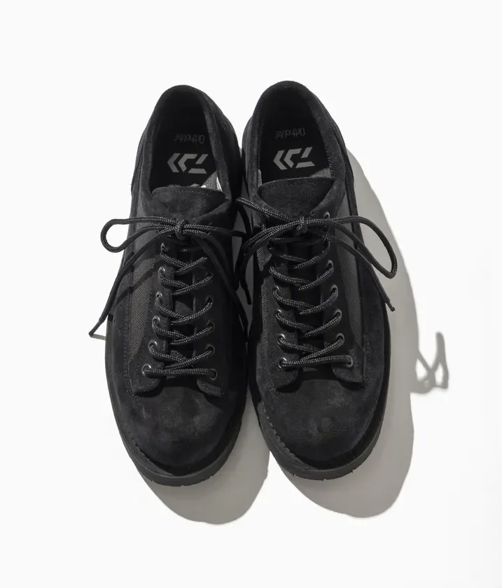 白い背景に置かれた黒いスエード調のレースアップシューズのペアです。