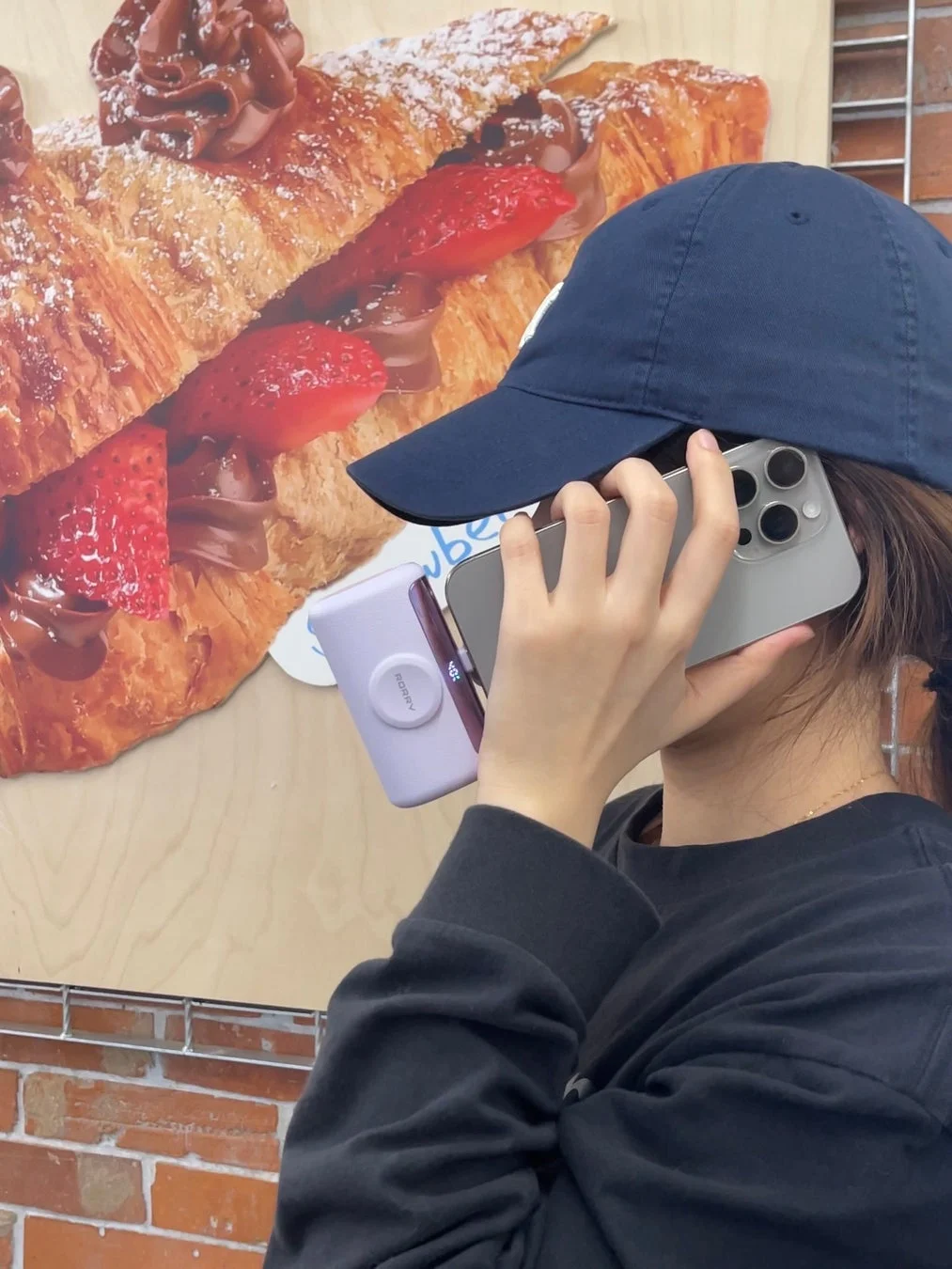 カフェでスマートフォンを顔に当てている人物